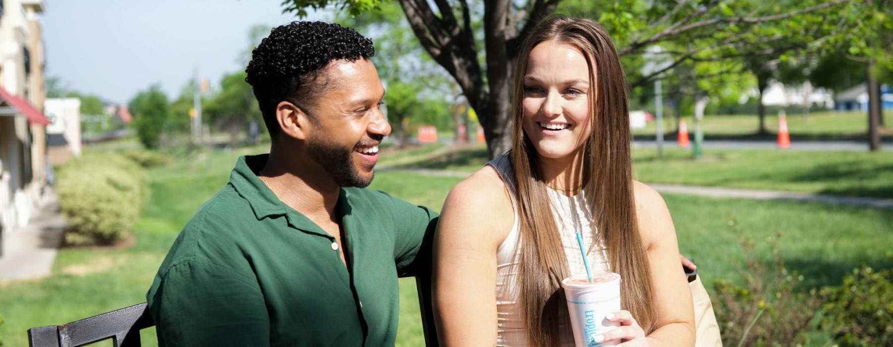 a man and woman sitting on a bench in a park